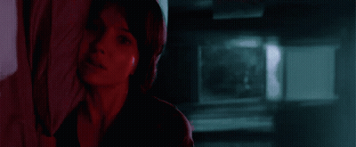 A Woman Is Looking Out A Window With A Blue Sky In The Background . GIF