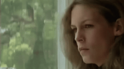 A Woman Is Looking Out Of A Window And Making A Serious Face . GIF