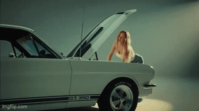 A Woman Is Looking Under The Hood Of A Gt 350 GIF