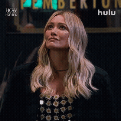 A Woman Is Looking Up In Front Of A Hulu Sign GIF