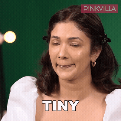 A Woman Is Making A Funny Face And The Word Tiny Is On Her Chest GIF