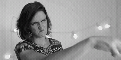 A Woman Is Making A Funny Face In A Black And White Photo While Holding Her Hand Up . GIF