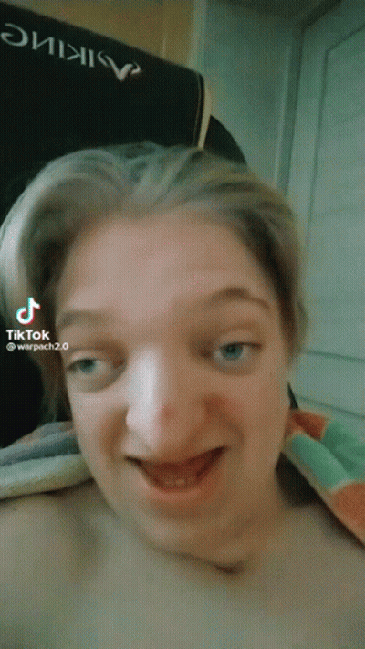 A Woman Is Making A Funny Face In Front Of A Chair That Says Warpach 2.0 GIF