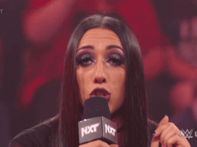 A Woman Is Making A Funny Face In Front Of A Crowd Of People . GIF