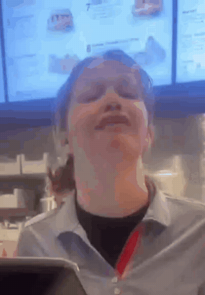 A Woman Is Making A Funny Face In Front Of A Menu In A Fast Food Restaurant . GIF
