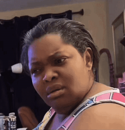 A Woman Is Making A Funny Face In Front Of A Mirror . GIF