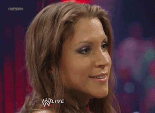 A Woman Is Making A Funny Face In Front Of A Sign That Says W Live GIF