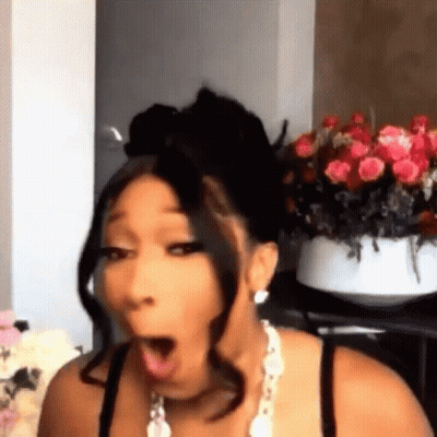 A Woman Is Making A Funny Face In Front Of A Vase Of Flowers . GIF
