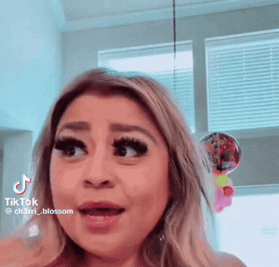 A Woman Is Making A Funny Face In Front Of A Window With Balloons In The Background . GIF