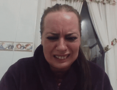 A Woman Is Making A Funny Face In Front Of A Window With Curtains GIF