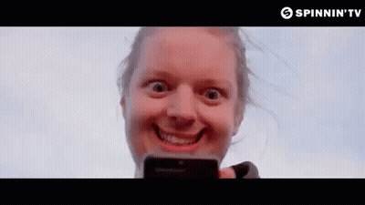 A Woman Is Making A Funny Face While Holding A Cell Phone In Her Hand . GIF