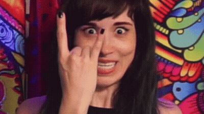 A Woman Is Making A Funny Face While Holding Her Finger To Her Nose . GIF