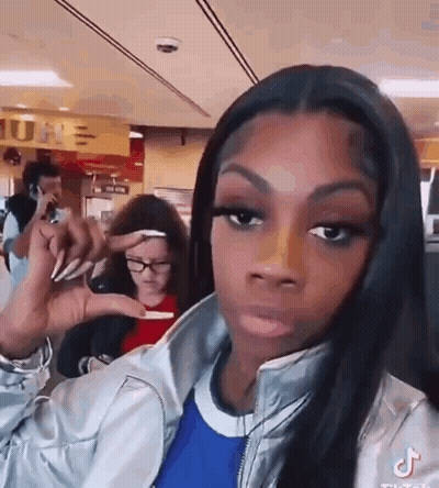 A Woman Is Making A Funny Face While Holding Something In Her Hand In A Restaurant . GIF
