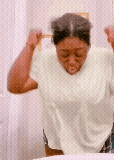 A Woman Is Making A Funny Face While Looking At Herself In The Bathroom Mirror . GIF