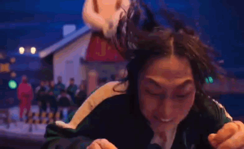 A Woman Is Making A Funny Face While Pointing At The Camera In Front Of A Mickey Mouse Statue . GIF