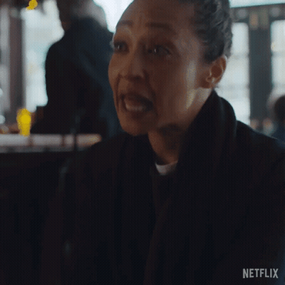 A Woman Is Making A Funny Face While Sitting At A Table In A Bar . GIF