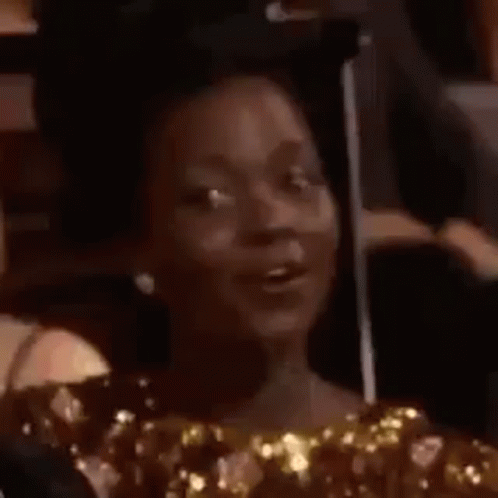 A Woman Is Making A Funny Face While Sitting In A Crowd Of People . GIF