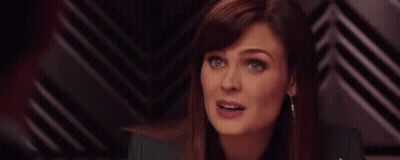 A Woman Is Making A Funny Face While Sitting In Front Of A Black And White Striped Wall . GIF