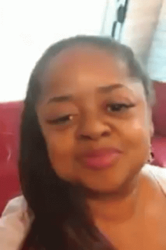 A Woman Is Making A Funny Face While Sitting On A Red Couch . GIF