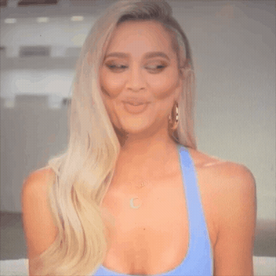 A Woman Is Making A Funny Face While Wearing A Blue Tank Top And Earrings . GIF
