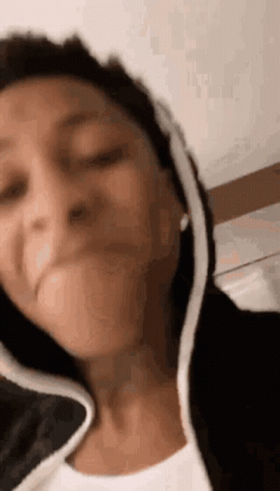 A Woman Is Making A Funny Face While Wearing A Hoodie . GIF