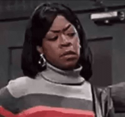 A Woman Is Making A Funny Face While Wearing A Striped Sweater And Earrings . GIF