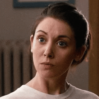 A Woman Is Making A Funny Face While Wearing A White Shirt . GIF