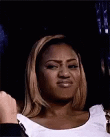 A Woman Is Making A Funny Face While Wearing A White Tank Top . GIF