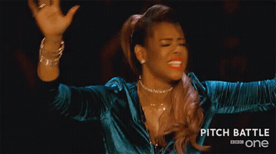 A Woman Is Making A Funny Face With Her Hands In The Air While Wearing A Blue Jacket . GIF