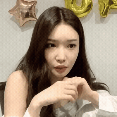 A Woman Is Making A Heart Shape With Her Hands In Front Of Balloons . GIF