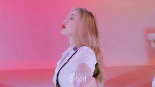 A Woman Is Making A Heart Shape With Her Hands While Wearing A White T-Shirt With Chanel On It . GIF