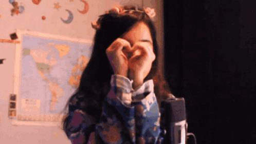 A Woman Is Making A Heart Shape With Her Hands GIF