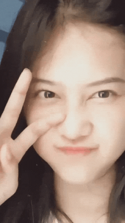 A Woman Is Making A Peace Sign With Her Hand GIF