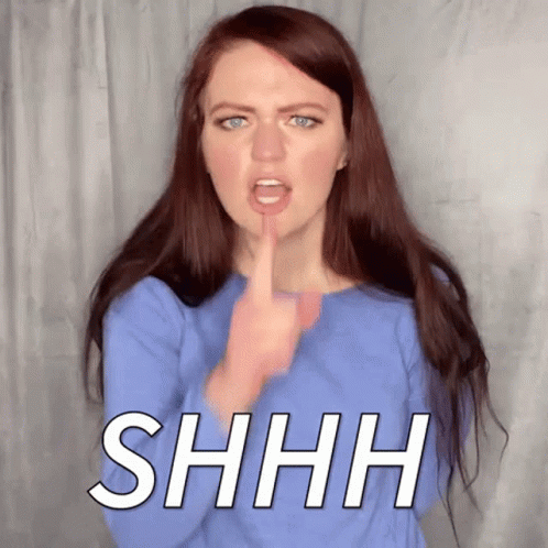 A Woman Is Making A Shhh Sign With Her Finger To Her Mouth . GIF