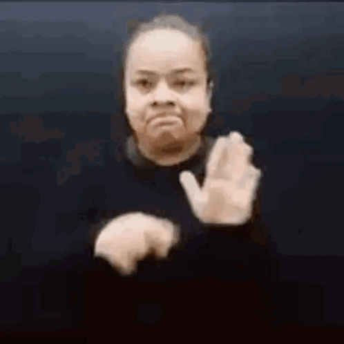 A Woman Is Making A Stop Sign With Her Hands In Front Of A Black Background . GIF