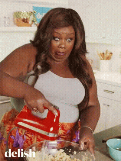 A Woman Is Mixing Something In A Bowl With A Red Mixer And The Word Delish Is On The Bottom Right GIF