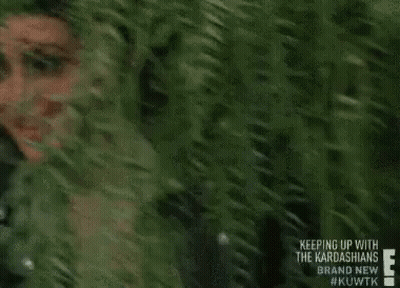 A Woman Is Peeking Out Of A Tree And Smiling . GIF