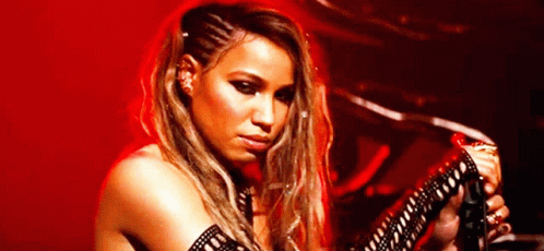 A Woman Is Playing A Guitar In Front Of A Red Background GIF