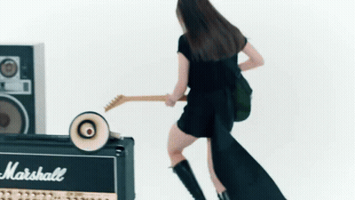 A Woman Is Playing A Guitar Next To A Marshall Amplifier . GIF
