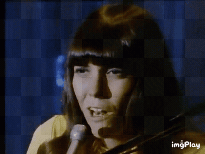 A Woman Is Playing A Violin In Front Of A Microphone . GIF