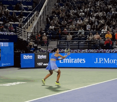 A Woman Is Playing Tennis In Front Of A Dubai Duty Free Banner GIF