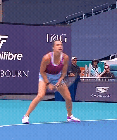 A Woman Is Playing Tennis In Front Of A Sign That Says Img On It GIF