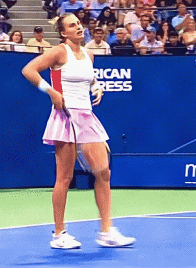 A Woman Is Playing Tennis On A Court With An American Press Sign Behind Her GIF
