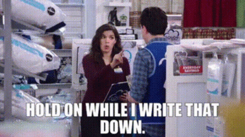 A Woman Is Pointing At A Man In A Store And Saying `` Hold On While I Write That Down . '' GIF