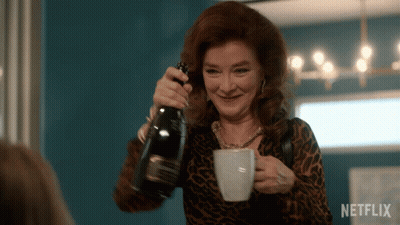 A Woman Is Pouring A Bottle Of Champagne Into A Cup With Netflix Written On The Bottom GIF