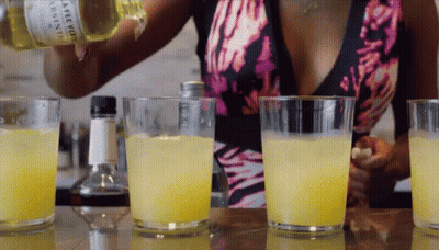 A Woman Is Pouring A Drink From A Bottle That Says ' Aloe Vera ' On It GIF