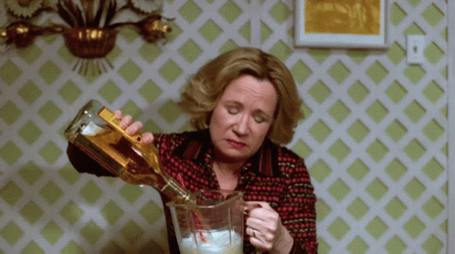 A Woman Is Pouring A Drink Into A Pitcher GIF