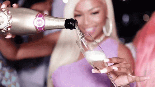 A Woman Is Pouring A Glass Of Champagne From A Silver Bottle GIF