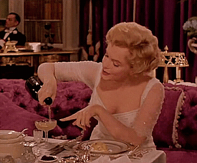 A Woman Is Pouring Wine Into A Glass GIF