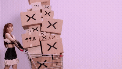 A Woman Is Pushing A Shopping Cart Filled With Boxes With X On Them GIF